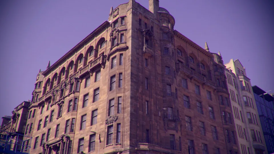 A tall stone building photographed from the corner beneath a purple-tinted sky