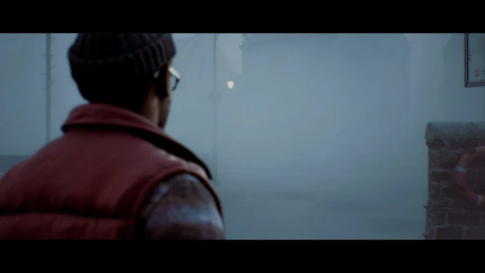 A man in a red vest looks down a foggy street with a stone wall and life ring