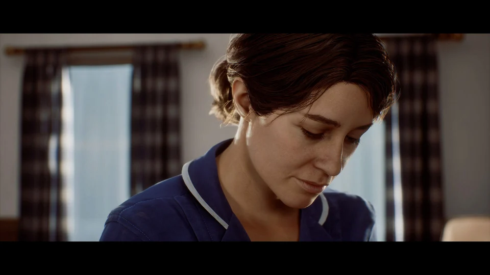 A brown-haired woman in a blue nurse’s uniform looks down, with a curtained window behind her